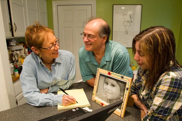 Shelley and Michael DeLaurentis, parents of Susanna, and their daughter, Lucy,in their kitchen, with photo of Susanna at age 2 on countertop, Elkins Park, November 8, 2011.  ( David M Warren / Staff Photographer )