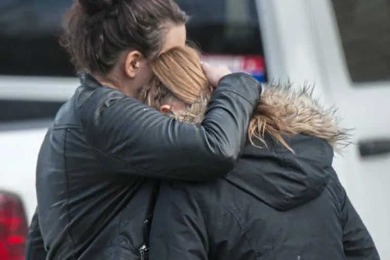Two people console each other near scene of shooting at a car wash in Fayette County, Pa.
