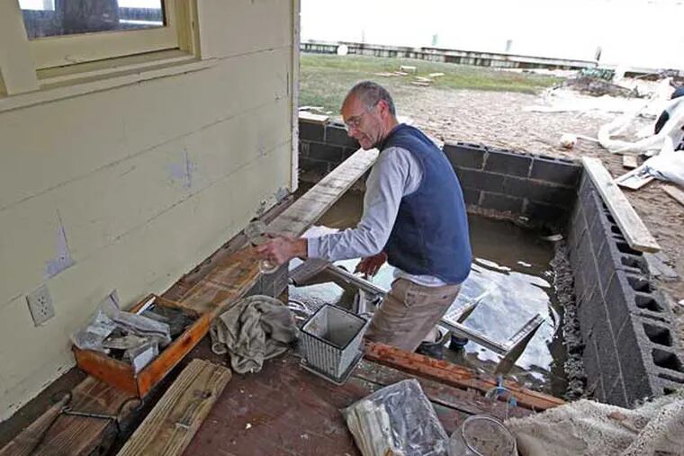 Paul McGarry of Bayshore Drive, Toms River, N.J., tries to salvage things from the water under their porch as he and his family pick through their home after Sandy. ( MICHAEL BRYANT / Staff Photographer )