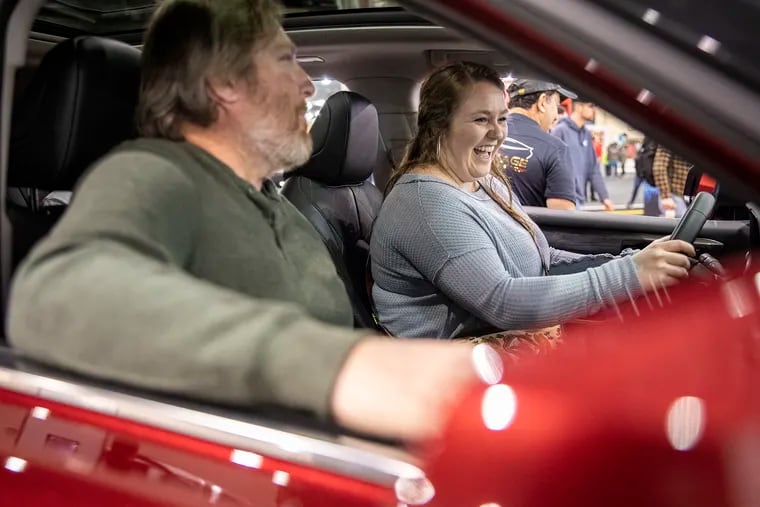 Jaden Tyrrell, 24, of West Philadelphia, sits in a Toyota Highlander with her father as they talk to a man through the speakers about the features of the vehicle at the Philadelphia Auto Show in the Convention Center on Saturday, opening day of the 10-day event.