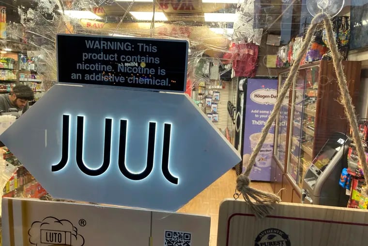 A Juul electronic cigarette sign hangs in the front window of a convenience store in New York City in June.