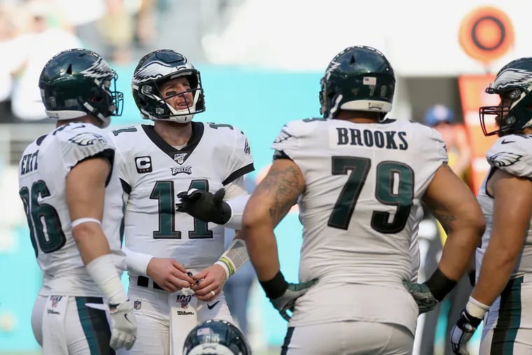 Eagles quarterback Carson Wentz (11) huddles with tight end Zach Ertz (86) and guard Brandon Brooks (79) during the game against the Dolphins.