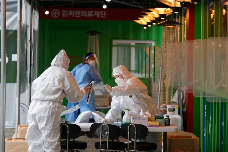 Medical workers wearing protective gear prepare to take samples at a temporary screening clinic for the coronavirus in Seoul, South Korea.