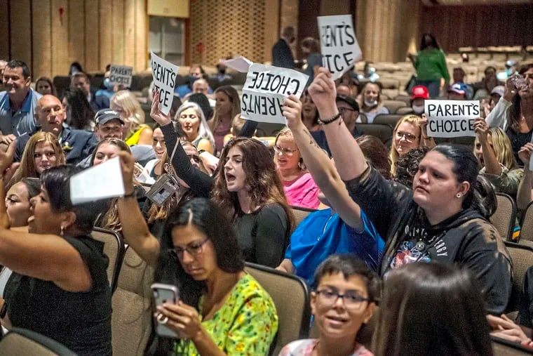 People hold signs and chant during an August meeting of the North Allegheny School District school board regarding the district's mask policy. School board candidates opposing mask mandates and lessons about racism in U.S. history won in red states and some politically divided districts but often came up short in their bids to shape policy for school districts over the newest culture war issue.