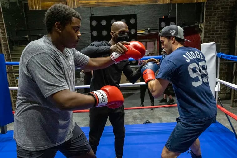 Philadelphia boxer Maleek Jackson working with the cast of "Rocky, the Musical" at the Walnut Street Theatre.  Rocky is played by Matthew Amira (right),  and Apollo Creed is played by Nichalas L. Parker.
