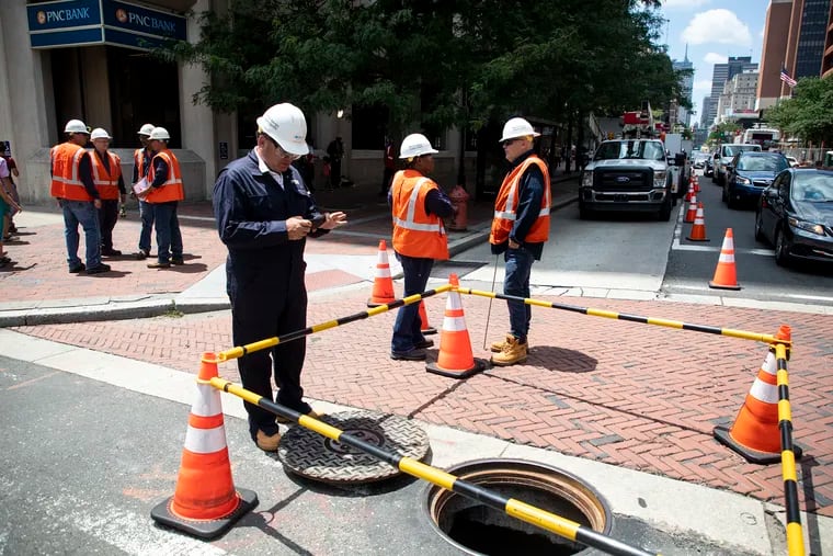 A Peco worker takes photos of the manhole at Fourth and Market Streets, where a fire caused a power outage to a few buildings in the area, including the National Museum of American Jewish History, the Independence Visitor Center and the Liberty Bell.