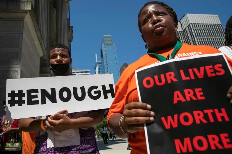 Students and staff including Axzaviyon Clark-Bolden (left), of Imhotep, hold signs as they attend a rally against gun violence at City Hall in Philadelphia on May 31.