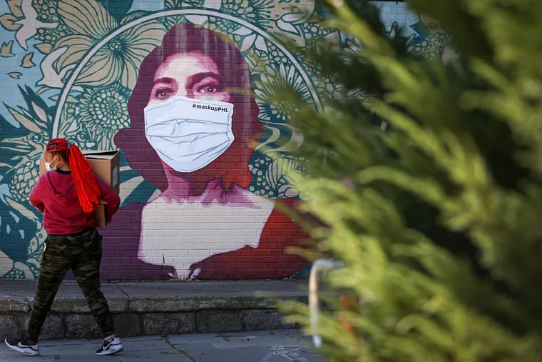 A woman walks by the Marian Anderson mural on the facade of the Marian Anderson Recreation Center in Philadelphia, Pa. on November 10, 2020. The mural has a temporary mask on it to encourage people to wear a mask during the coronavirus pandemic.