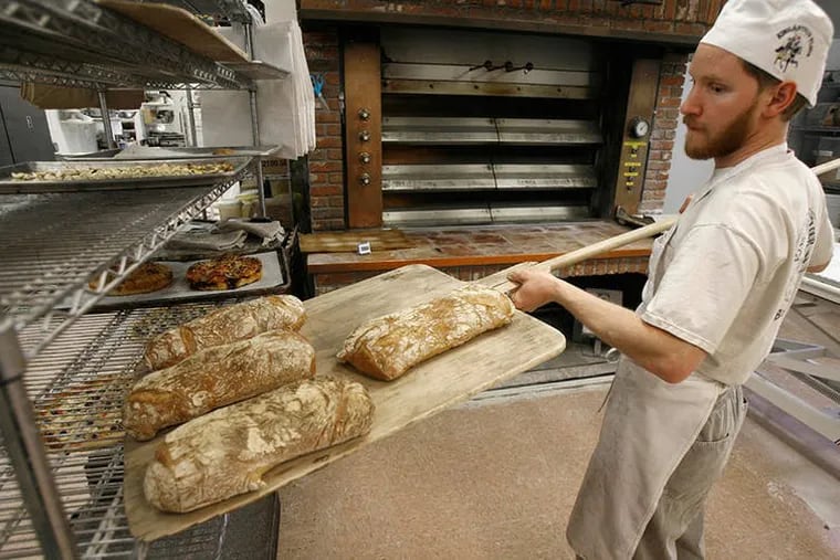 An employee at employee-owned King Arthur Flour Co. in Norwich, Vermont, takes bread from the oven.