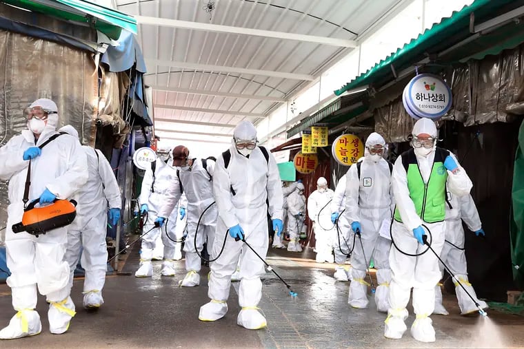 Workers wearing protective suits spray disinfectant as a precaution against the coronavirus at a market in Bupyeong, South Korea, Monday, Feb. 24, 2020. South Korea reported another large jump in new virus cases Monday a day after the the president called for "unprecedented, powerful" steps to combat the outbreak that is increasingly confounding attempts to stop the spread. (Lee Jong-chul/Newsis via AP)