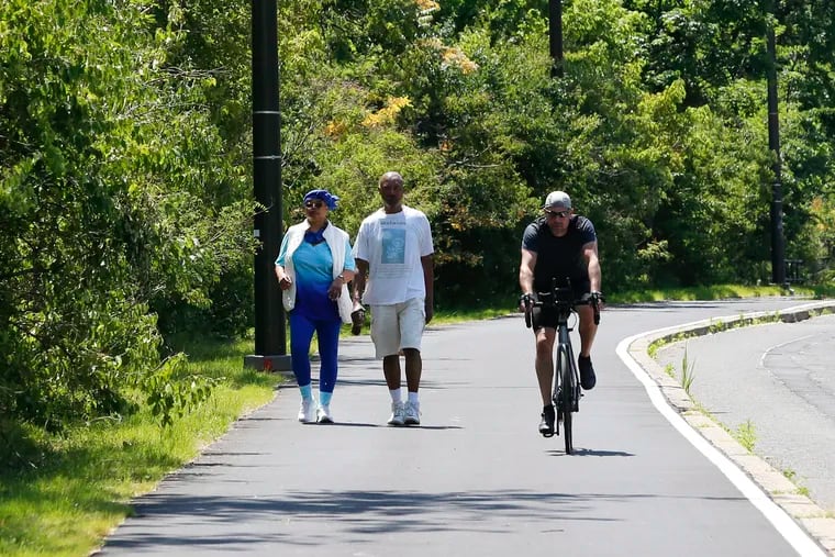 Walkers and a biker use the newly paved recreation path/sidewalk on Martin Luther King Drive.