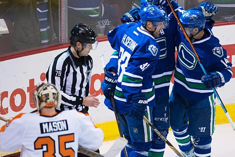 Vancouver Canucks' Alex Burrows (14) celebrates his goal with Daniel Sedin and Henrik Sedin as Philadelphia Flyers goalie Steve Mason (35) looks on during the third period of NHL action in Vancouver, Canada Tuesday, March. 17, 2015. (AP Photo/The Canadian Press, Jonathan
Hayward)