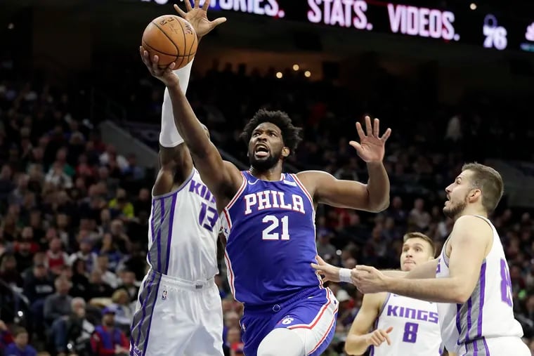 Sixers Joel Embiid splits Kings defenders on his way to the net during first quarter.