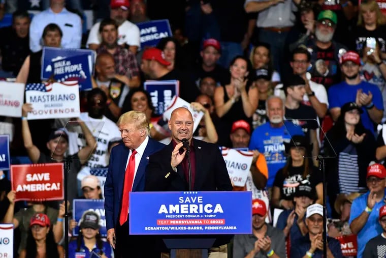 Doug Mastriano, Republican candidate for Pennsylvania governor, speaks at the podium with former President Donald Trump during a September rally in Wilkes-Barre, Pa. Candidates who've questioned or denied the results of the 2020 presidential election are on the ballot in 48 of the 50 states, including 10 Republicans running for office in Pennsylvania.