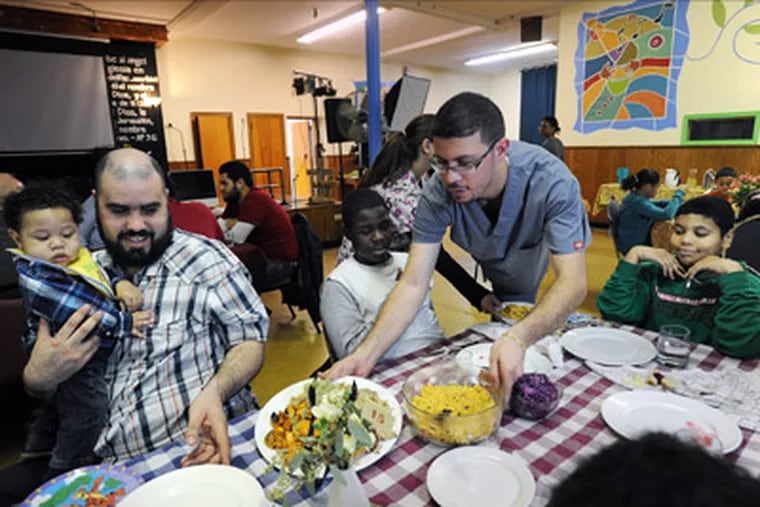 Sunday Suppers at the West Kensington Ministry is a program founded by Linda Samost after she read the Hunger series in the Inquirer. (from left) Being served Thanksgiving dinner are Phoenix Montes, 9 months, Jorge Montes, his dad, also Sherrod Nixon, 13, being served by Tim Nassar,  and Eric Montes, 10  also waiting for the food. Nov. 20, 2011 ( Sharon Gekoski-Kimmel / Staff Photographer )