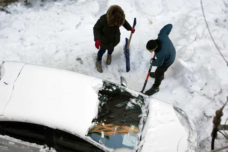 Two people dig their vehicle out from frozen snow and ice along N. 13th St. near Hamilton in Philadelphia on Wednesday morning.