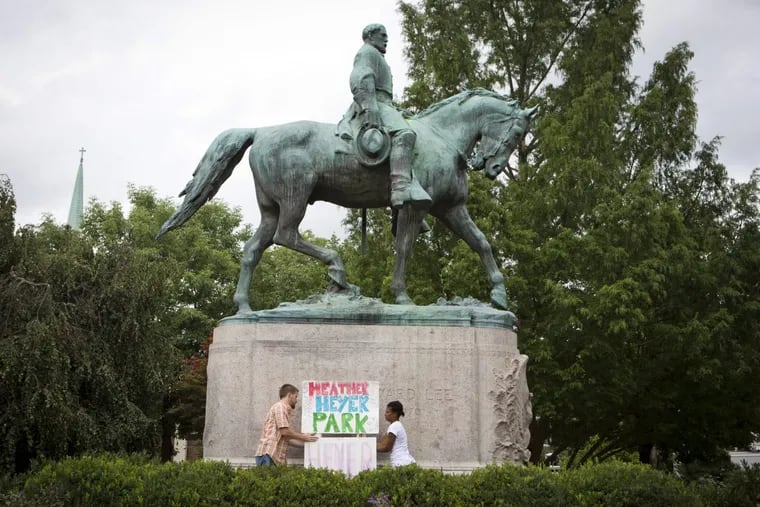 Charlottesville, VA – August 15: Tom Lever, 28, and Aaliyah Jones, 38, both of Charlottesville, put up a sign that says &quot;Heather Heyer Park&quot; in front of the Robert E. Lee monument in Emancipation Park Tuesday, August 15 in Charlottesville, Va. (Photo by Julia Rendleman for The Associated Press)
