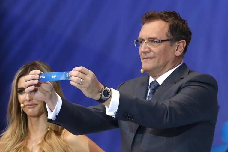 FIFA Secretary General Jerome Valcke shows the ticket of USA during the draw ceremony for the 2014 soccer World Cup in Costa do Sauipe near Salvador, Brazil, Friday, Dec. 6, 2013. (AP Photo/Andre Penner)