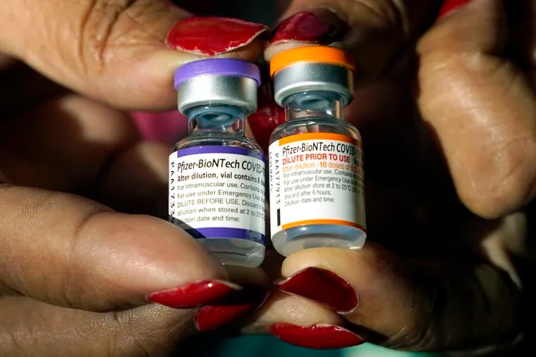 A nurse holds a vial of the Pfizer COVID-19 vaccine for children ages 5 to 11 (right) and a vial of the vaccine for adults, which has a different colored label, at a vaccination station in Jackson, Miss.