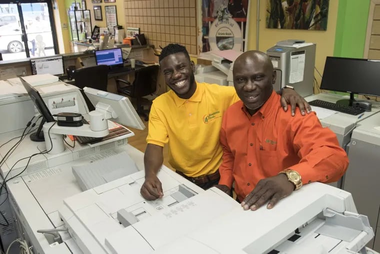 Jude Arijaje (right), 51, is grooming his son Mejire, 23, to eventually take over the family’s Minuteman Press Copying and Printing center on 1717 S. Broad St.