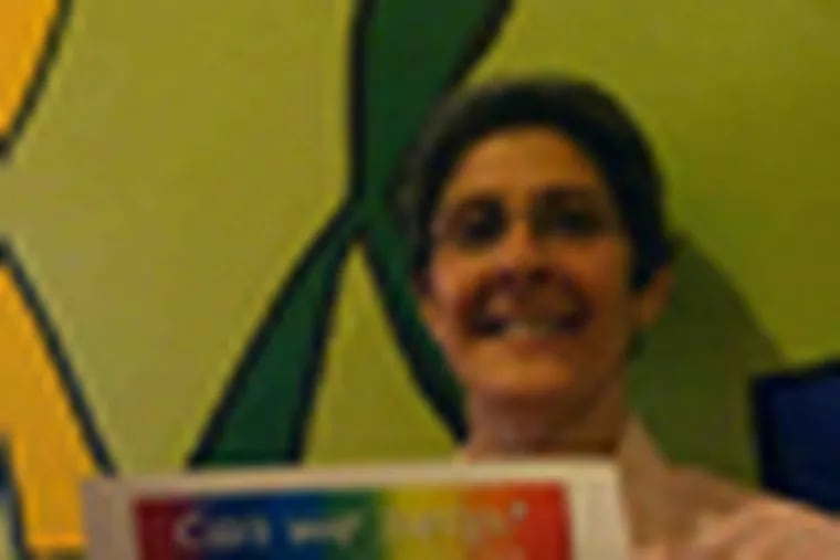 Caption:  Carrie Jacobs, founder and executive director of The Attic Youth Center in Center City, shows the concept design for 100 advertisements that will appear on SEPTA buses and subway cars this month. The ads are the key element in a campaign to attract youths struggling with homophobic bullying at school. credit: Gregory Thomas