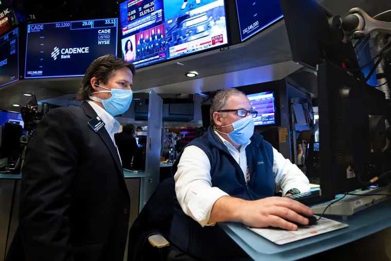 In this photo provided by the New York Stock Exchange, trader Michael Conlon, right, works on the floor, on Tuesday.