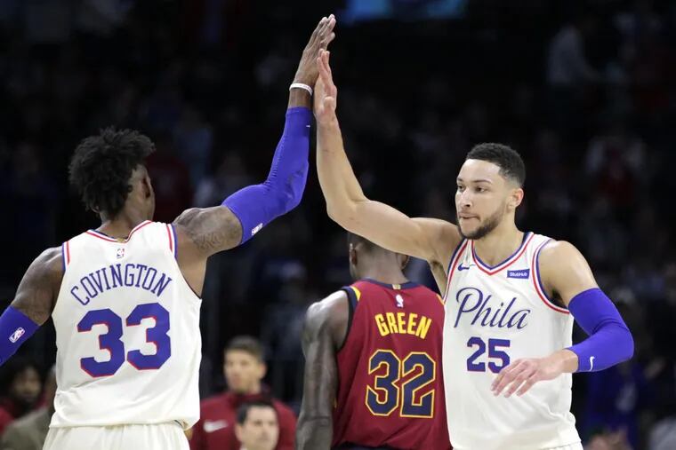 Robert Covington, left, high-fives Ben Simmons of the Sixers during a run against the Cavaliers during the first half at the Wells Fargo Center on April 6, 2018.