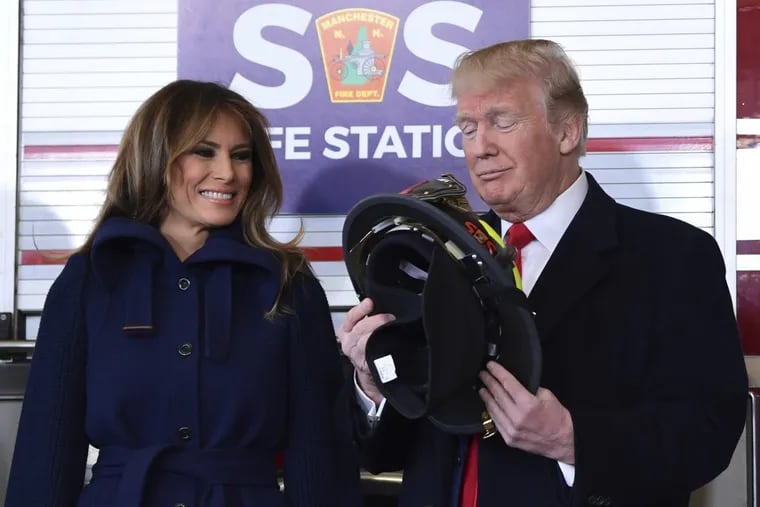 President Trump and first lady Melania Trump look over a helmet he received from Manchester City Fire Chief Daniel Goonan during a visit to the Manchester Central Fire Station in Manchester, N.H., Monday.