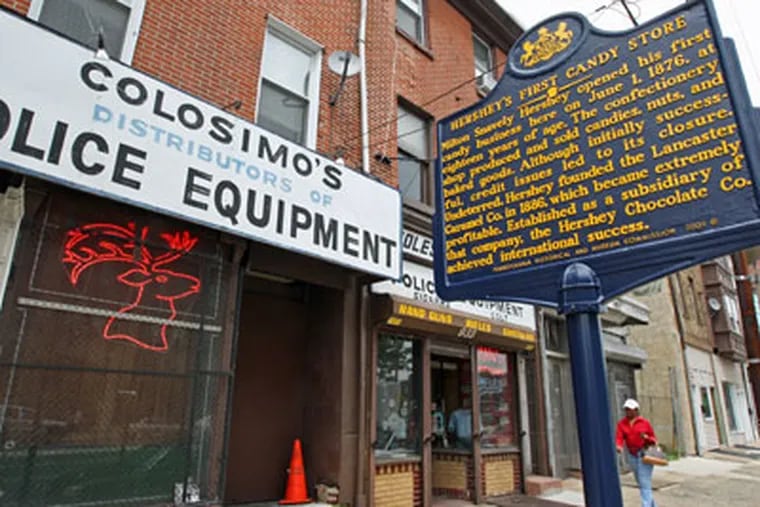 A historical marker honors the site of Milton Hershey's first candy shop. It is in front of Colosimo's gun store on Spring Garden Street. (Michael Bryant / Staff Photographer)