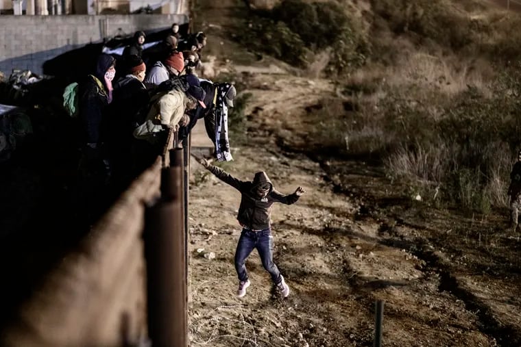 A migrants jumps the border fence to get into the U.S. side to San Diego, Calif., from Tijuana, Mexico, Tuesday, Jan. 1, 2019.