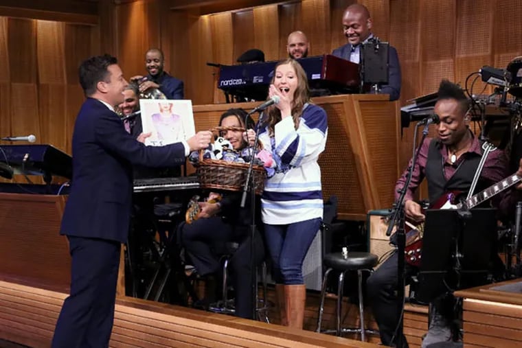 Jimmy Fallon gives a gift basket to Villanova Pep Band piccolo player Roxanne Chalifoux, who played with The Roots on March 23, 2015. (Photo by: Douglas Gorenstein/NBC)