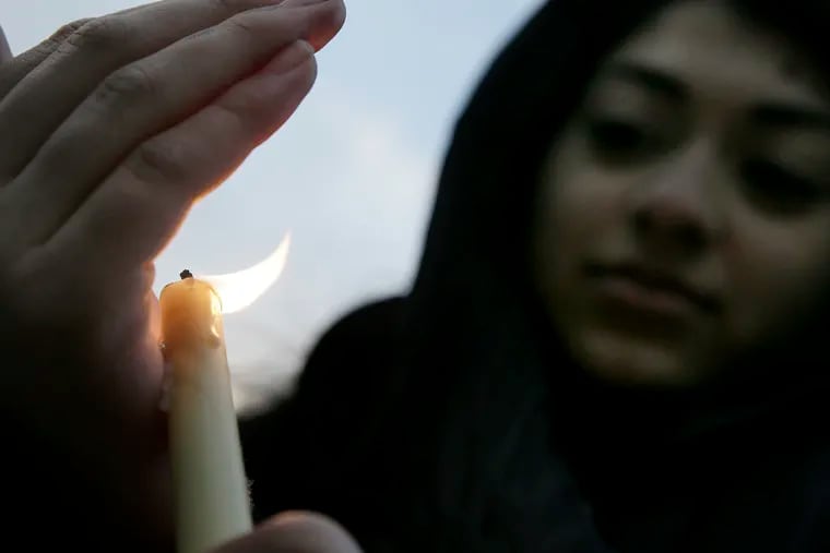 Sanaa Amanullah, 15, of Collegeville, holds a candle during a vigil at LOVE Park Saturday for the Muslims killed in New Zealand last week. The vigil was sponsored by the Philadelphia chapter of the Council on American-Islamic Relations.