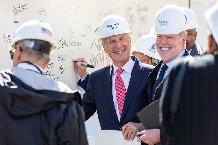 Jerry Sweeney, CEO of Brandywine Realty Trust (center) and Drexel University President John Fry (right) sign a large beam that was later placed atop Brandywine's building at 3151 Market St. in the Schuylkill Yards development.