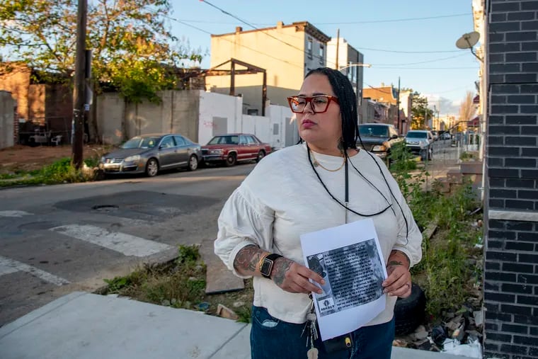 Carmen Pagan poses Nov. 10, 2020 with a flyer she has been distributing, on the corner where her 20-year-old son was recently shot three times. He survived, but she's been struggling to keep him away from the streets for years. She's now hitting the streets trying to find out who shot him, but her son continues to slip away.