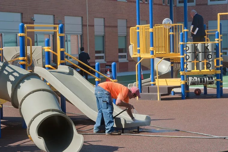 KIPP’s playground receives a last-minute sprucing-up before Wednesday’s dedication. (Avi Steinhardt/For The Inquirer)