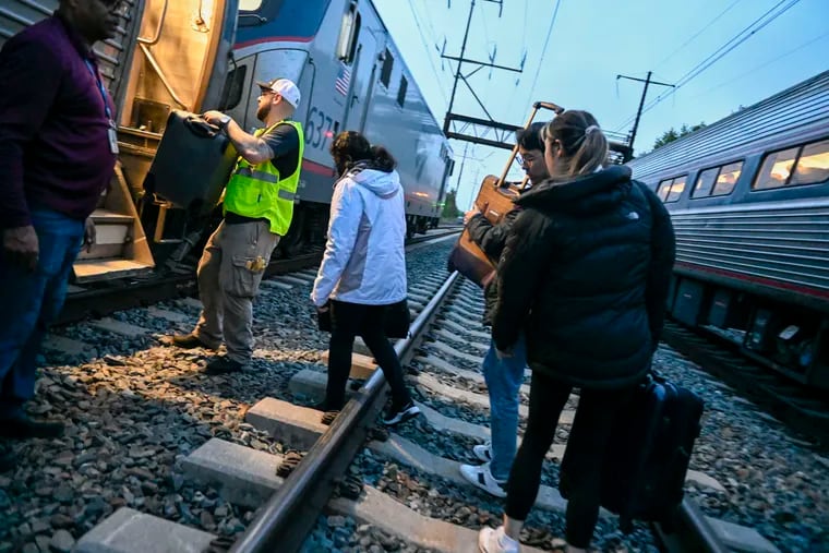 Amtrak personnel help passengers board a new train Saturday after their original train, headed from New York to Washington, struck and killed two juveniles on the tracks in Chester.