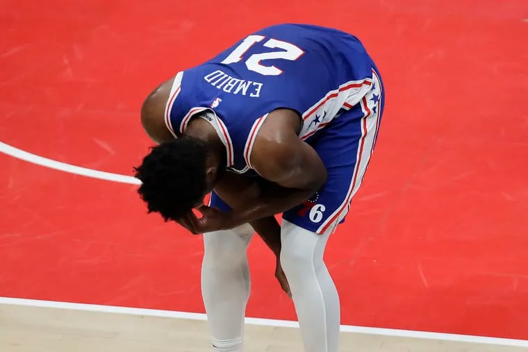 Sixers center Joel Embiid  reacts after falling down while driving to the basket during the first quarter.