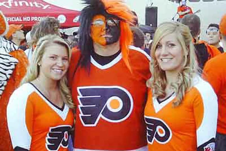 Ed Slivak, center, who used to ask the Kate Smith statue for help before Flyers playoff games, now turns to Flyers Ice Girls Jessica Myers, left, and Kimberly Webb, right, for good luck.