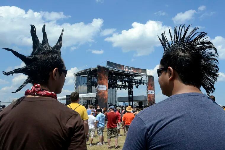 Ruben Marza, left, 24, and his brother Marcelo Marza,, 26, listen to the band The Sword, on stage at Orion Music + More at Bader Field in Atlantic City June 23, 2012. They came from Fairfax, VA along with another sibling, Javier, 22. They only do up the hair for "the big concerts. We do this for every big festival," the elder Marza said. ( TOM GRALISH / Staff Photographer )