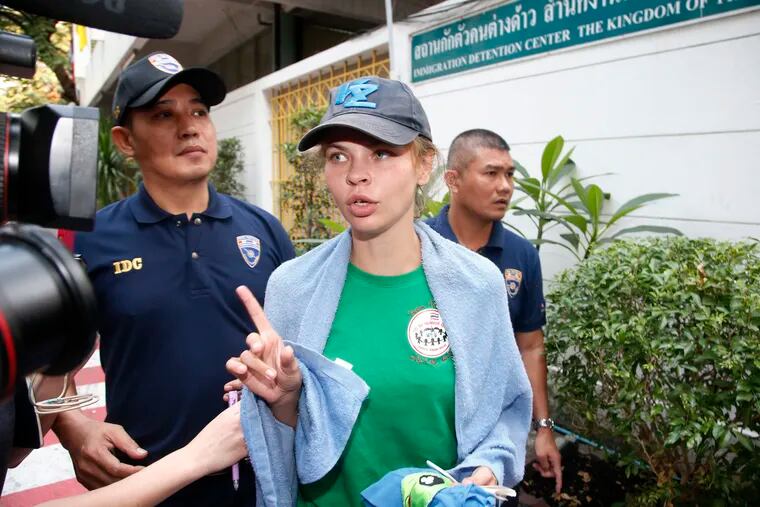 Belarusian model Anastasia Vashukevich talks to journalists as she is escorted from the Immigration Detention Center towards a vehicle to take her to an airport for deportation in Bangkok, Thailand, Thursday, Jan. 17, 2019. Thai officials say they are deporting Vashukevich who claimed last year that she had evidence of Russian involvement in helping elect Donald Trump president. (AP Photo/Sakchai Lalit)