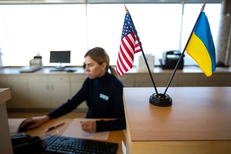 The Ukrainian and U.S. flags on display at a counter of the Ukrainian Selfreliance Credit Union in Feasterville, where teller Julia Gromyak works on an account.