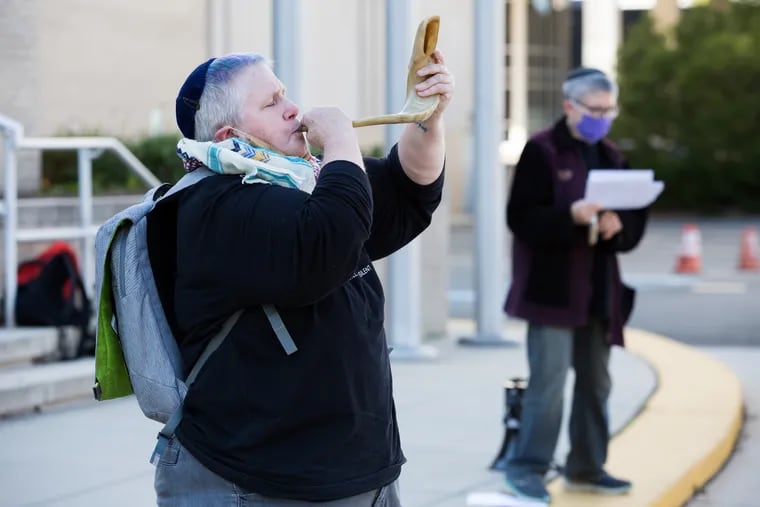 Elliott Battzedek blows the shofar at a Tashlich, a casting out of what needs to be left behind for the Rosh Hashanah holiday, in front of the Philadelphia School District Headquarters on September 20, 2020. While Tashlich is normally done by a body of water, Rabbi Linda Holtzman (right) chose to lead this ceremony in front of the school district headquarters to make a statement about racism-based inequities in funding for public schools. (RACHEL WISNIEWSKI / For the Inquirer)