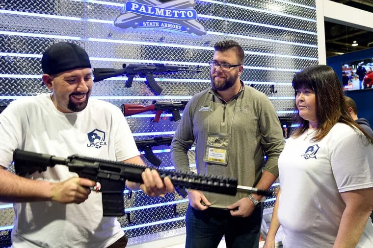 Palmetto State Armory chief marketing officer Adam Ruonala (center) helps Leonard Marovich handle a PSA AR10, along with Lisa Mesich (right). Post election gun sales took a big dip in the nation, an interesting quirk that proves America's commerce is often driven on pure fear.