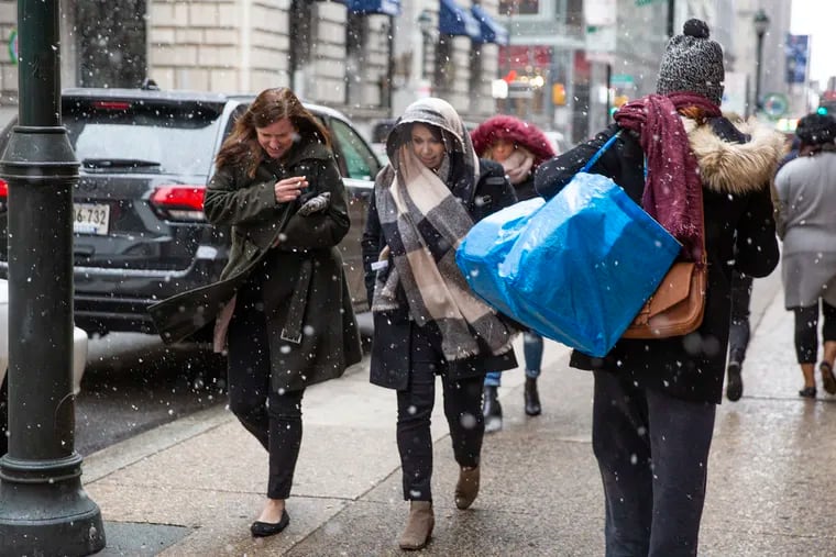 Pedestrians walk along 15th street as snow falls in Philadelphia on Wednesday, Dec. 05, 2018.
