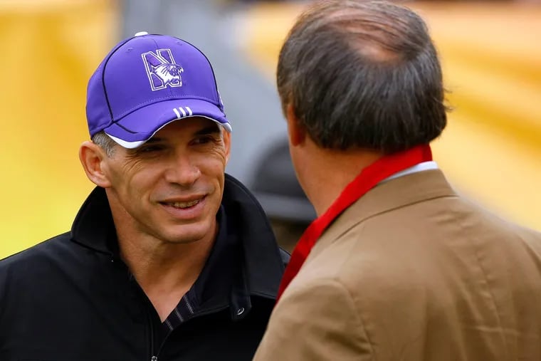Joe Girardi, wearing a Northwestern cap, talking to a member of the Outback Bowl committee during the bowl game between the Wildcats and Auburn in January 2010.