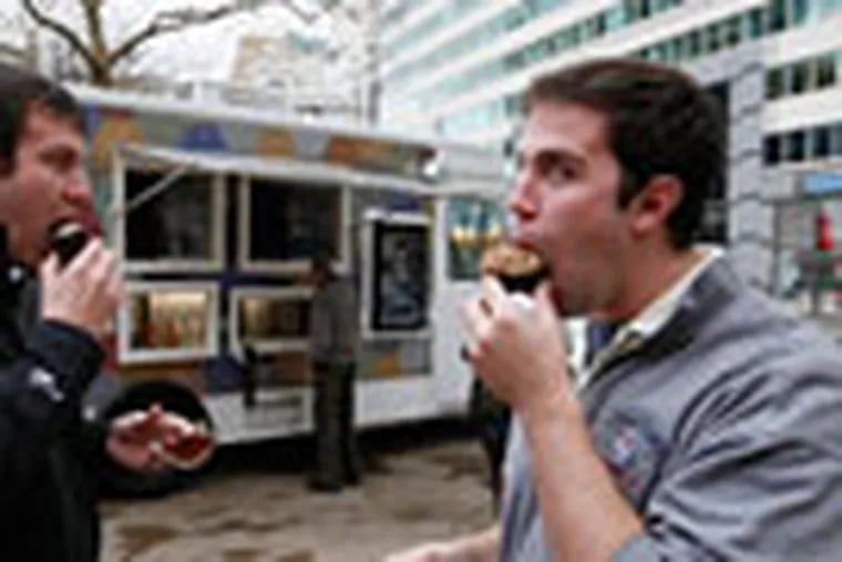 Andy Campbell (left) and Brian Wing (right) eat cupcakes purchased from the Cupcake Truck.