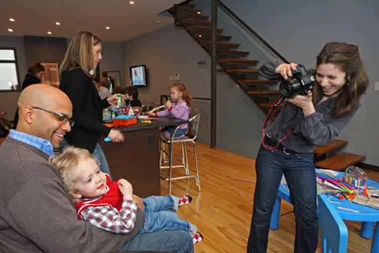 Laura Novak, right, waits for just the right moment between Bret Perkins and his son, Tiernan Perkins, 21 months old, during a Winter Solstice party. ( Michael Bryant / Staff Photographer )