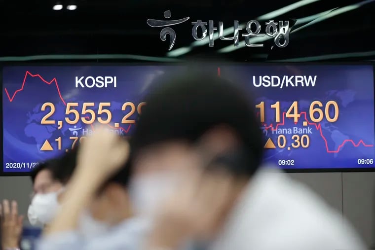 Currency traders watch computer monitors near screens showing the Korea Composite Stock Price Index (KOSPI), left, and the foreign exchange rate between U.S. dollar and South Korean won at the foreign exchange dealing room in Seoul, South Korea, Monday, Nov. 23, 2020.