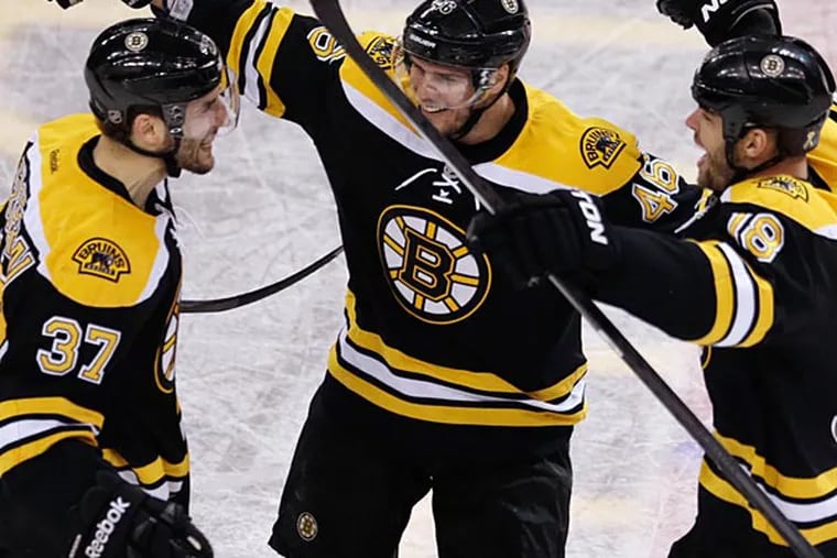 Bruins center Patrice Bergeron (37) rejoices with  David Krejci  (center) and Nathan Horton after his
goal in the final minute of the third period that tied it. (Charles Krupa / AP)