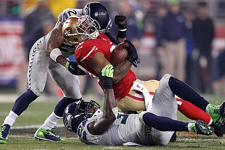 49ers running back Carlos Hyde is tackled by Seahawks safeties Earl Thomas and Kam Chancellor. (Cary Edmondson/USA Today Sports)